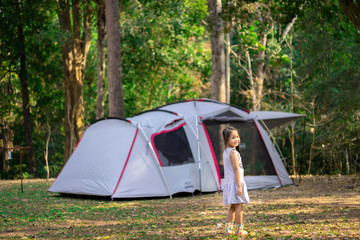 little girl standing in front of tent while going camping.The concept of outdoor activities and adventures in nature.