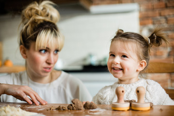 Obraz na płótnie Canvas Mother and daughter baking cookies in their kitchen