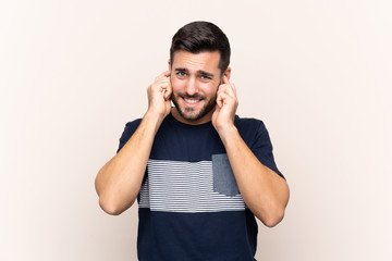 Young handsome man with beard over isolated background frustrated and covering ears