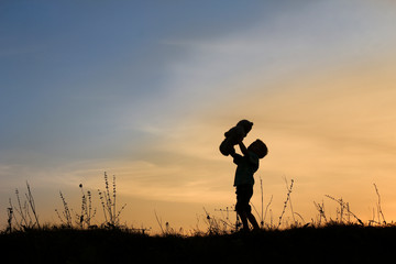 silhouette of little boy with bear on sunset