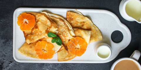 crepes with citrus, jam and berries (thin pancakes, mandarin, blueberry) menu concept. background. top view. copy space