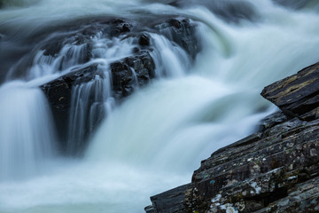 Fototapeta premium Long exposure shot of the waterfalls in Glen Orchy near Bridge of Orchy in the Argyll region of the highlands of Scotland during winter whilst the river is flowing fast from rainfall