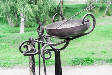 Tools for torture at medieval festival close-up. On metal stand hangs leather whip, tongs and bowl...
