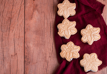 Shortbread cookies with meringue in the form of a flower, on a light wood background.