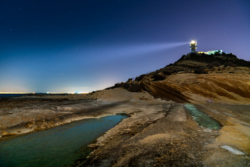 lighthouse lit on cliff at night