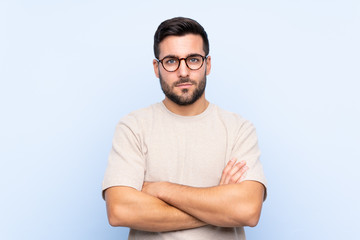 Fototapeta premium Young handsome man with beard over isolated blue background keeping arms crossed