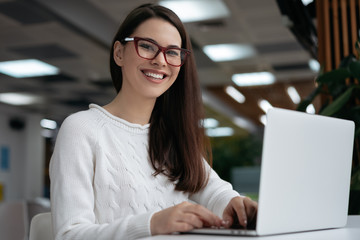 Portrait of happy copywriter working freelance project, typing, looking at camera and smiling....
