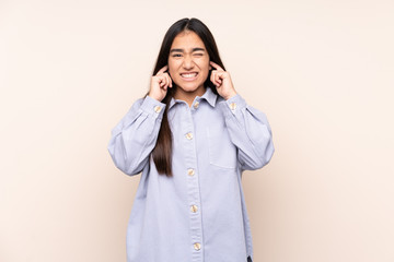 Young Indian woman isolated on beige background frustrated and covering ears