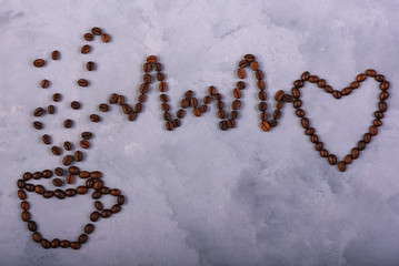 Cup and heart made from roasted coffee beans on concrete background. Concept