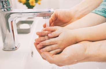 Father helps his son to wash his hands under the water
