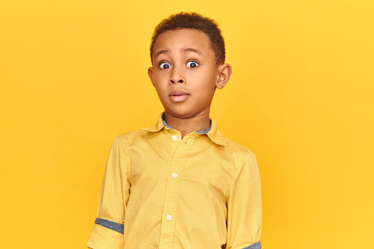 Are you serious? Funny little dark skinned boy expressing total bewilderment, raising eyebrows, staring at camera, being shocked with adult content while surfing internet or watching television
