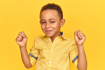 Success, triumph, joy and happiness concept. Adorable cute excited little Afro American boy having...