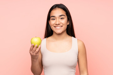 Fototapeta na wymiar Young Indian woman isolated on pink background with an apple