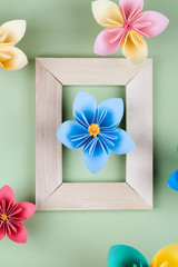 blue paper flower in wooden frame on green background.