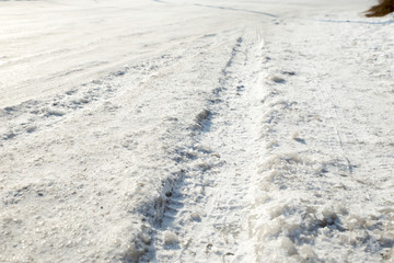 Track from a wheel on an icy track. Dangerous driving conditions. Icy road with tracks from the wheels of cars. The concept of safe driving on a winter slippery track.
