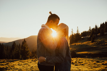 Romantic young couple kissing passionately at sunset, mountains on background, feelings and relationships concept. Beautiful couple kissing during sunset. 
