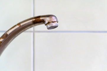 Old rusty drinking tap with a drop of water on a light background close-up. 