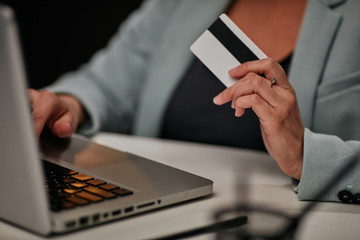 Young caucasian businesswoman sitting in her office and using credit card to pay subscription for licensed software.