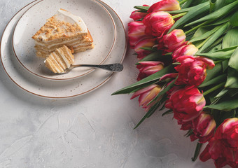a piece of cake, on a light backdrop, tulip flowers on the side, copy space