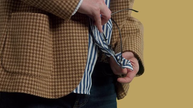 b-roll closeup of man clean his glasses using a shirt wearing on and then put his hands onpocket of his vintage jacket