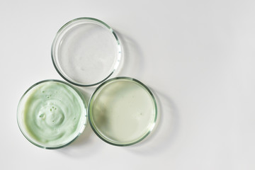 Glass petri dishes with shampoo, shower gel and serum with copy space, above
