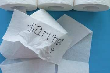 Rolls of white toilet paper labeled "diarrhea" on a blue background. Close up.