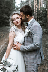 the bride and groom kiss in the forest at the wedding ceremony. selective focus. film grain.