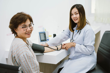 young female doctor checking senior patient  blood pressure. Health care.