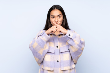 Young Indian woman isolated on blue background showing a sign of silence gesture