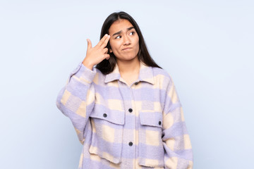 Young Indian woman isolated on blue background with problems making suicide gesture
