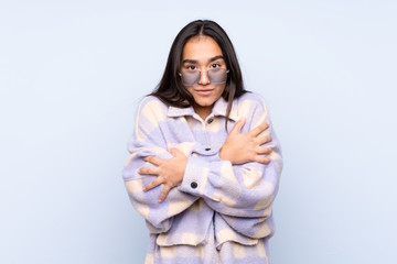 Young Indian woman isolated on blue background freezing