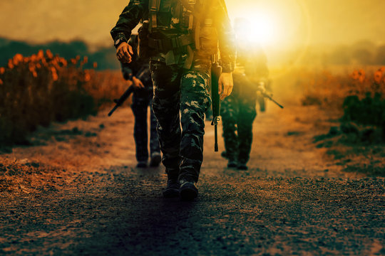 soldier with long rifle gun walking on dirt battle field