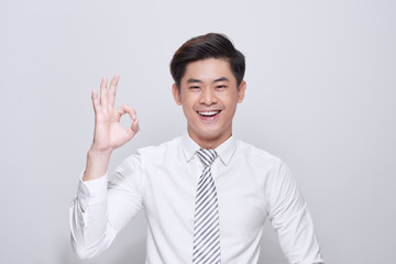 Portrait of a cheerful young man showing okay gesture isolated on the white background