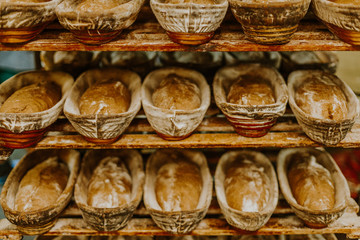 Baking bread. Dough in proofing basket on wooden table with flour, cumin and wheat ears. Top view.