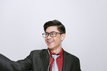 Happy adult man wearing earphones holding mobile phone looks at screen