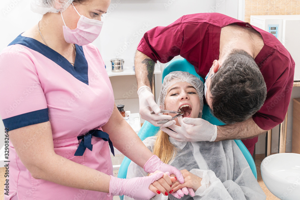 Wall mural dentist pulls out a tooth