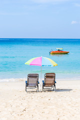 Beach chair under the colorful umbrella on the white sand beach, summer break, outdoor day light, paradise island