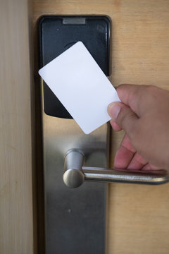 Man hand use key card switch in to open hotel room door.