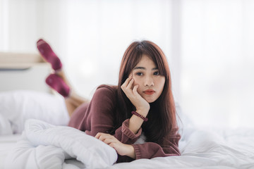 Portrait of beautiful young Asian woman is lying in bed with white curtain background.