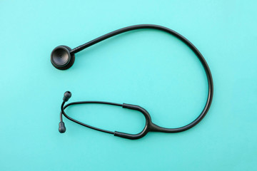 Black modern stethoscope on light blue background.