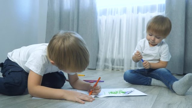 children draw with felt-tip pens in an album. little boy and girl concept childhood lifestyle brother and sister play paint on the floor with colored markers