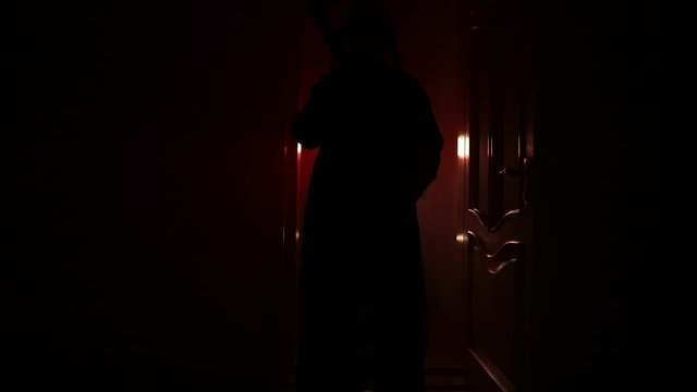 Silhouette of an unknown shadow figure on a door through a closed glass door. Spooky silhouette girl at night with smoke in background