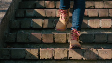 Close-Up Low-Angle Shot of Unrecognizable Woman in Yellow Boots and Jeans Walking DownStairs on Old Stone Stairs