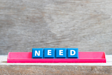 Tile letter on red rack in word need on wood background