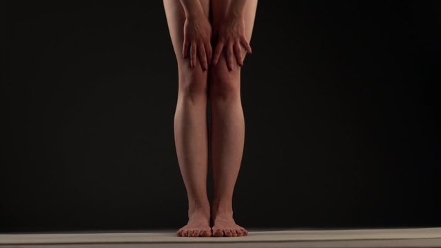Girl practicing yoga. Stretching arms and legs. Hands touching feet and gorund.