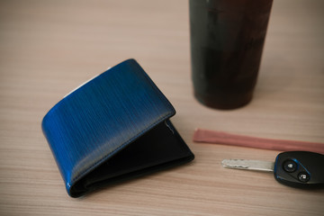 Blue wallet, car key and ice coffee