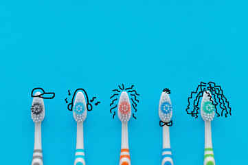 Colorful toothbrushes on a blue background in the form of cartoon characters. The view from the top. Close up. Concept of family hygiene.