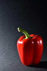 whole red bulgarian pepper on a black background vertical orientation