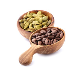 Coffee beans in a wooden spoon with cardamom on white background.