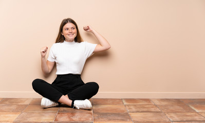 Fototapeta premium Ukrainian teenager girl sitting on the floor celebrating a victory